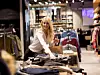 Eine Frau die in einer Boutique Klamotten sortiert