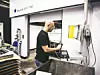 Mann steht in einer Werkhalle und bedient das Display einer Laserschneidanlage von Trumpf.