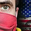 Ein Mann mit Maske, dahinter die Fahne der USA
