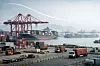 Blick auf einen chinesischen Containerhafen mit Kränen, Containern und Frachtschiffen als Symbol für schwächeres Exportwachstum und belastete Lieferketten.