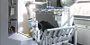 Weißer Industrieroboter in einer Fabrik neben Fördertechnik und Metallgestellen.