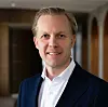 Mann im dunkelblauen Anzug vor unscharfem Innenraumhintergrund. KI-Rechenzentren-Experte Johan Rauer, Partner bei McKinsey