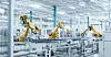 Gelbe Industrieroboter in einer modernen Fabrikhalle mit Förderbändern und weißen Metallstrukturen.
