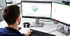 Person sitzt am Schreibtisch vor zwei Monitoren und arbeitet am Computer.
