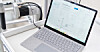 Laptop mit geöffneter Steuerungssoftware neben einer angeschlossenen Maschine.