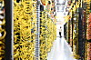 Serverracks in einem Rechenzentrum mit gelben Kabeln und einer Person im Gang.