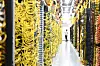 Serverracks in einem Rechenzentrum mit gelben Kabeln und einer Person im Gang.