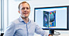 Mann neben Monitor mit technischer 3D-Ansicht eines PC-Gehäuses