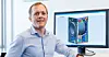 Mann neben Monitor mit technischer 3D-Ansicht eines PC-Gehäuses
