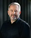 Porträt eines Mannes mit grauem Haar und Bart vor dunklem Hintergrund. Stefan Weinzierl, Chefredakteur des Fachmediums PRODUKTION (Moderation)